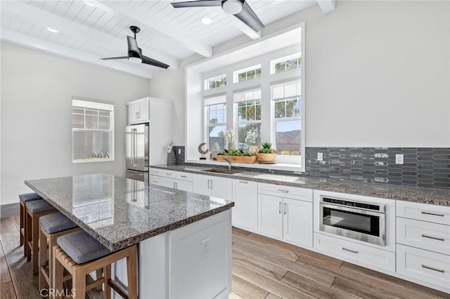 kitchen featuring a kitchen island, oven, high end refrigerator, and white cabinets