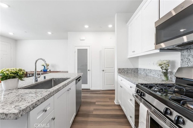 kitchen with appliances with stainless steel finishes, sink, white cabinets, and dark hardwood / wood-style flooring