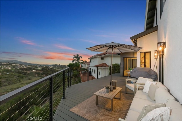 deck at dusk featuring area for grilling and an outdoor living space