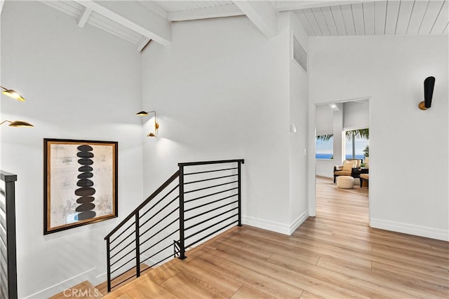 staircase featuring lofted ceiling with beams and wood-type flooring