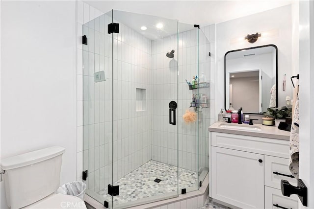 bathroom featuring vanity, a shower with shower door, and toilet