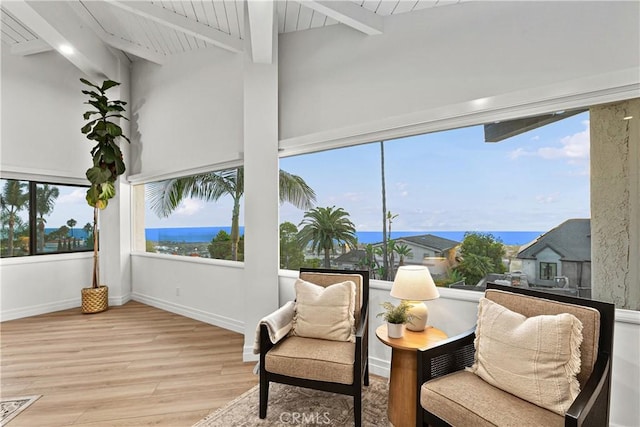 sitting room with lofted ceiling with beams, baseboards, and wood finished floors