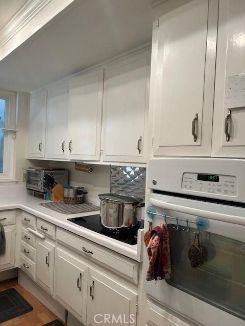 kitchen with white cabinetry, black electric cooktop, and white oven