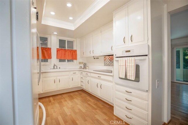 465 Avenida Sevilla Unit C, Laguna Woods, CA 92637 - kitchen featuring white appliances, crown molding, a sink, a raised ceiling, and light wood finished floors
