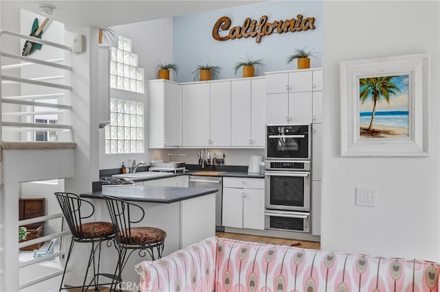 kitchen with appliances with stainless steel finishes, kitchen peninsula, a breakfast bar area, and white cabinets