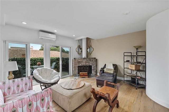 living room featuring a high end fireplace, a wall mounted air conditioner, and light hardwood / wood-style floors