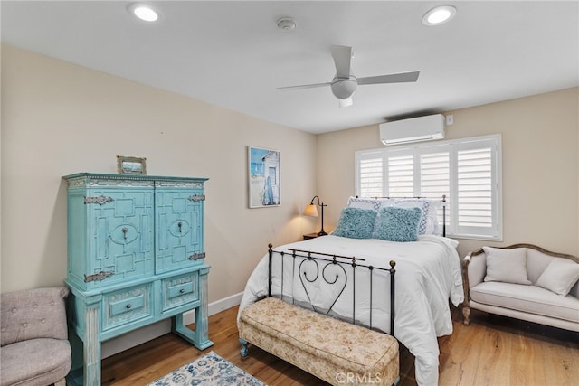 bedroom featuring a wall mounted air conditioner, wood-type flooring, and ceiling fan