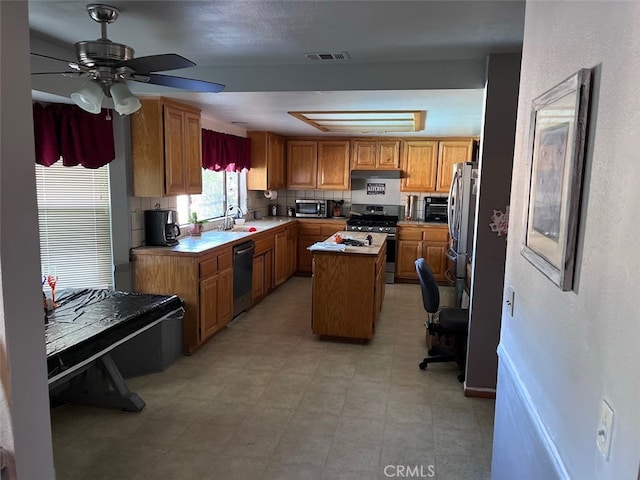 kitchen with a kitchen island, appliances with stainless steel finishes, sink, and ceiling fan