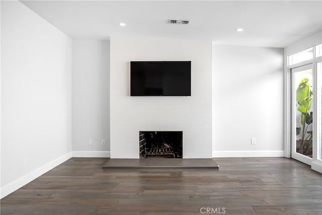 unfurnished living room featuring dark wood-type flooring and a fireplace