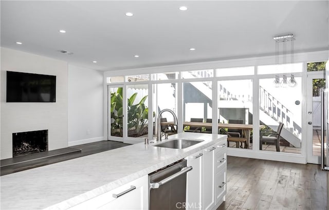 kitchen featuring dark wood-type flooring, sink, a large fireplace, dishwasher, and white cabinets