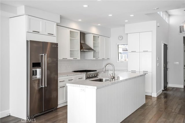 kitchen with wall chimney exhaust hood, sink, a center island with sink, and premium appliances