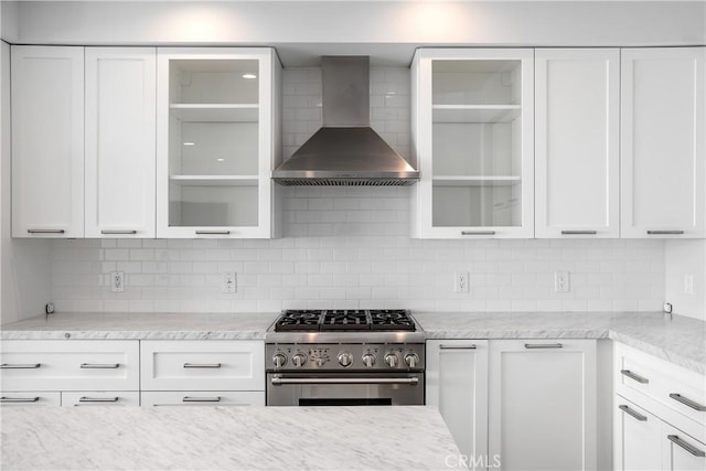 kitchen featuring high end stainless steel range oven, white cabinetry, backsplash, and wall chimney exhaust hood