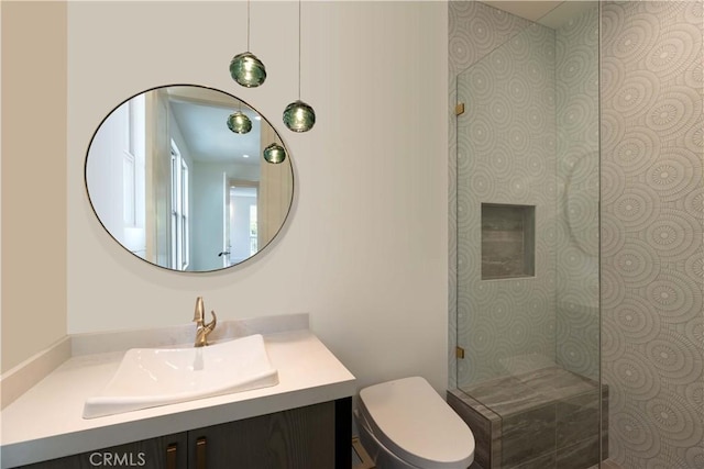 bathroom with vanity, toilet, and tiled shower