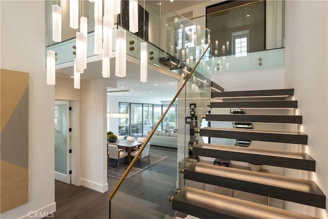 stairway with hardwood / wood-style flooring and a towering ceiling