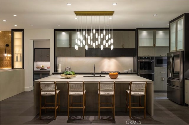 kitchen featuring hanging light fixtures, an island with sink, appliances with stainless steel finishes, and sink