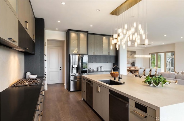 kitchen with sink, black dishwasher, stainless steel refrigerator with ice dispenser, a center island with sink, and decorative light fixtures