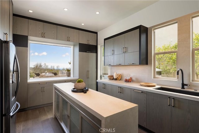 kitchen featuring gray cabinets, a center island, sink, and stainless steel refrigerator