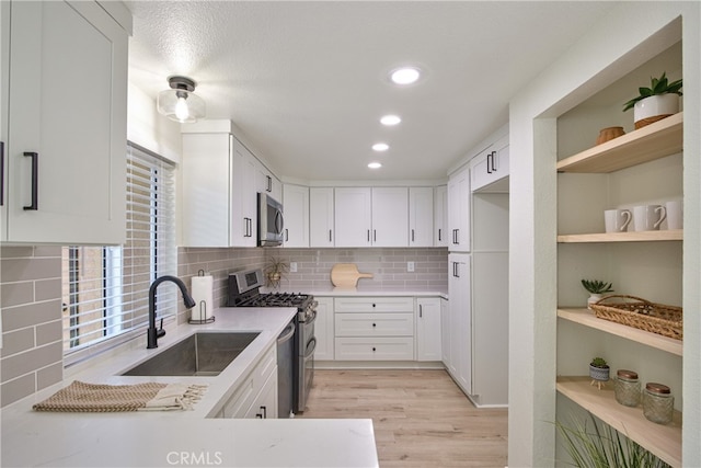 kitchen with stainless steel appliances, sink, and white cabinets