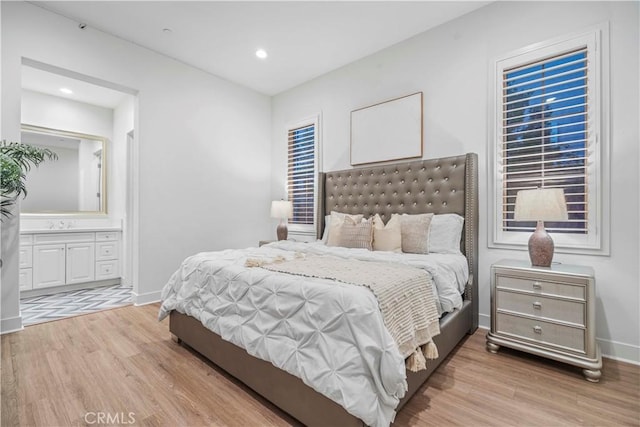 bedroom featuring ensuite bath and light hardwood / wood-style floors