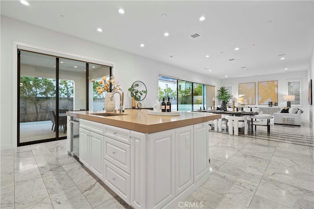 kitchen with white cabinetry, sink, and an island with sink