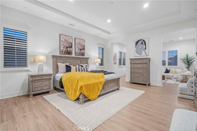 bedroom with a raised ceiling and light hardwood / wood-style floors