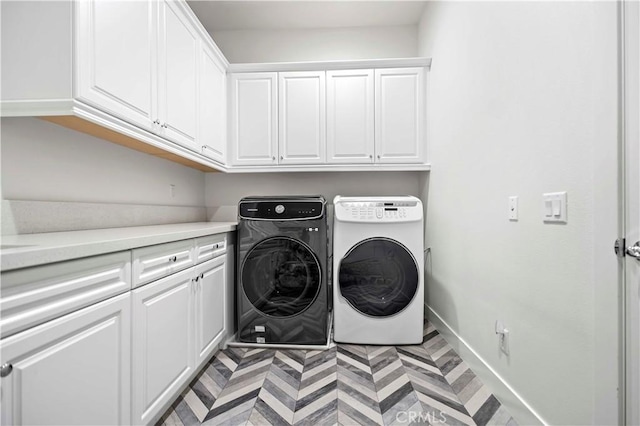 clothes washing area featuring independent washer and dryer and cabinets