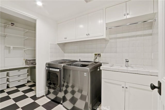 laundry area featuring cabinet space, light floors, independent washer and dryer, and a sink