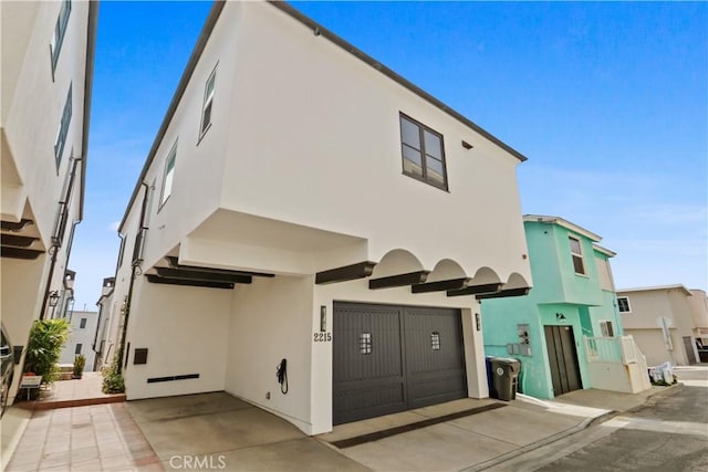 view of front of house with concrete driveway, an attached garage, and stucco siding