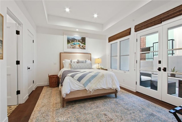 bedroom with a raised ceiling, wood finished floors, recessed lighting, french doors, and baseboards