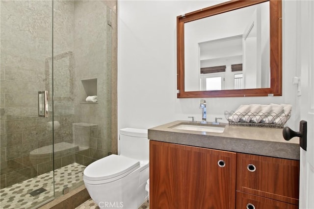 bathroom with toilet, a shower stall, and vanity