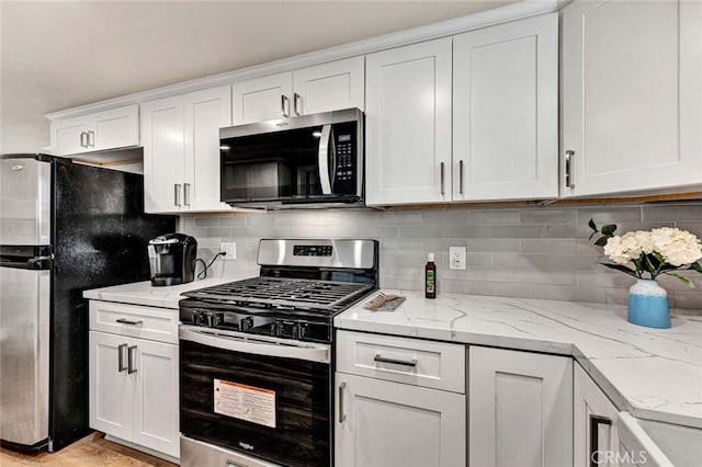 kitchen with backsplash, white cabinets, and appliances with stainless steel finishes