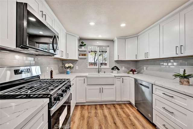 kitchen featuring sink, white cabinetry, stainless steel appliances, tasteful backsplash, and light hardwood / wood-style floors