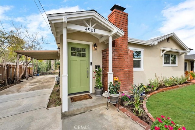 entrance to property featuring a lawn and a carport