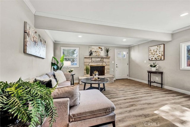 living room featuring ornamental molding, a stone fireplace, and hardwood / wood-style floors