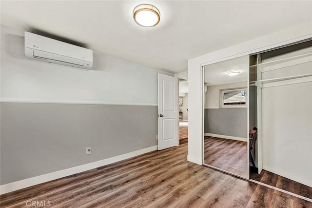 unfurnished bedroom featuring hardwood / wood-style floors, a closet, and a wall mounted AC