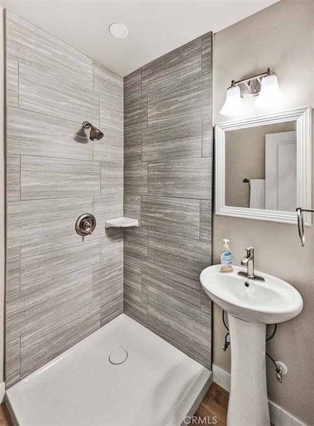 bathroom featuring wood-type flooring and a tile shower