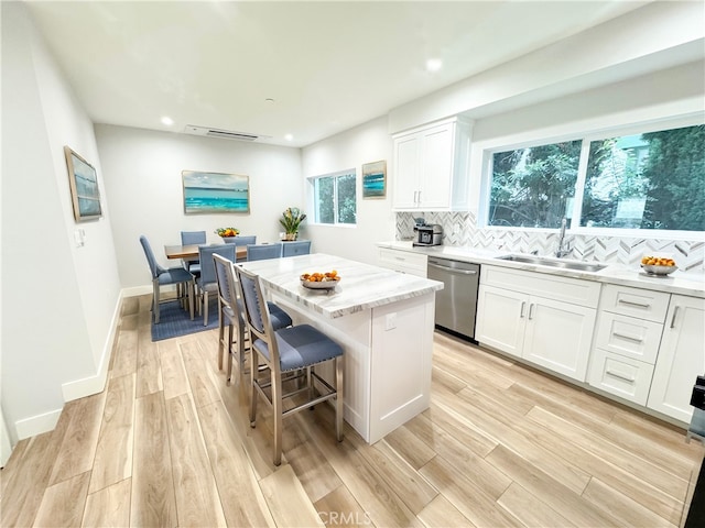 kitchen featuring a kitchen island, white cabinetry, dishwasher, sink, and backsplash