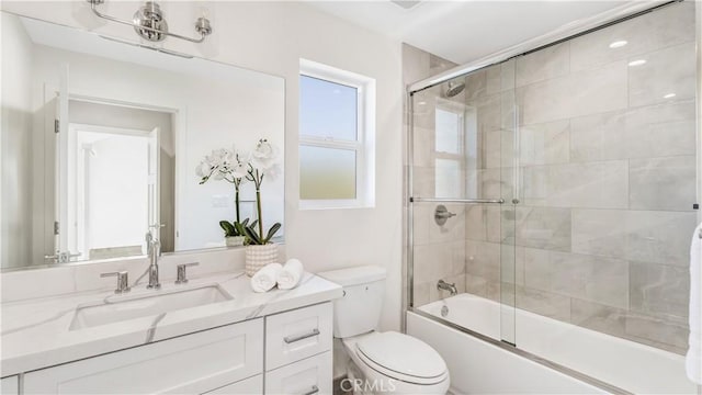 full bathroom with enclosed tub / shower combo, vanity, and toilet