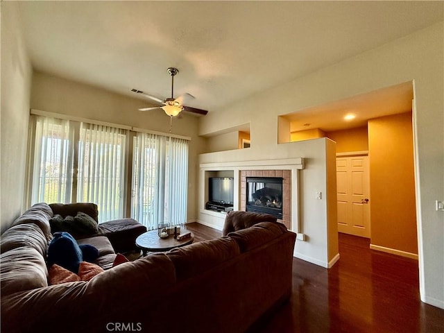 living room featuring dark hardwood / wood-style floors, ceiling fan, and a fireplace