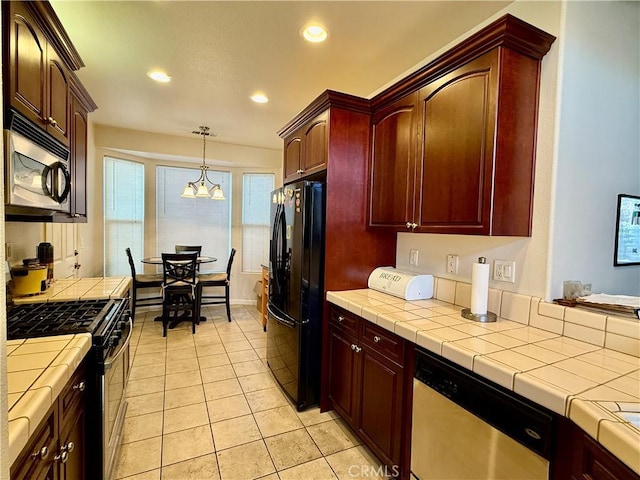 kitchen with light tile patterned flooring, appliances with stainless steel finishes, tile countertops, and hanging light fixtures