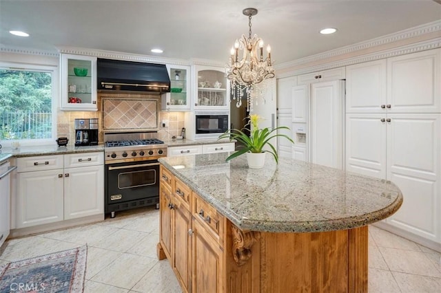 kitchen featuring white cabinets, a center island, built in appliances, light stone counters, and wall chimney range hood