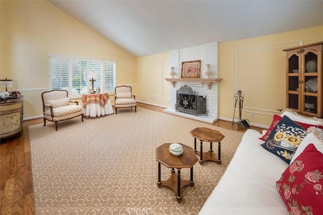 living room with a fireplace, vaulted ceiling, and hardwood / wood-style floors