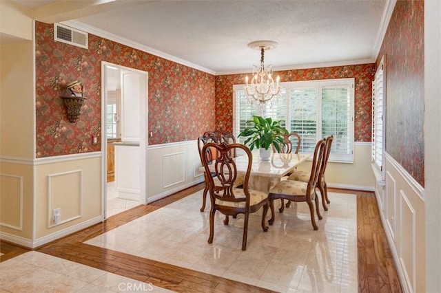 dining space with ornamental molding, a notable chandelier, and light wood-type flooring