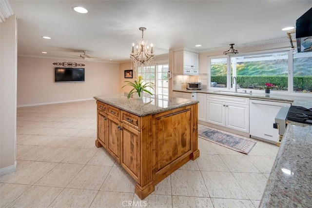 kitchen with sink, white cabinetry, hanging light fixtures, light stone counters, and decorative backsplash