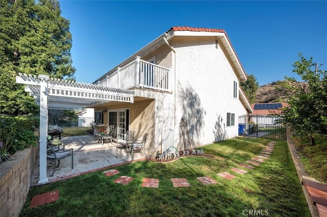 rear view of house with a balcony, a patio, a pergola, and a lawn