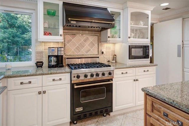 kitchen featuring premium range hood, luxury stove, light stone counters, and white cabinets