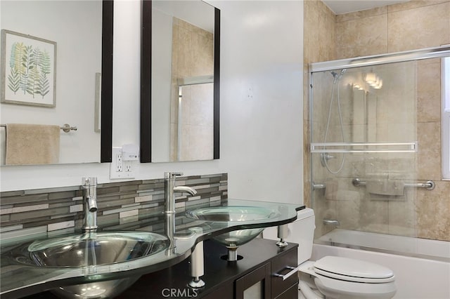 full bathroom featuring vanity, decorative backsplash, bath / shower combo with glass door, and toilet