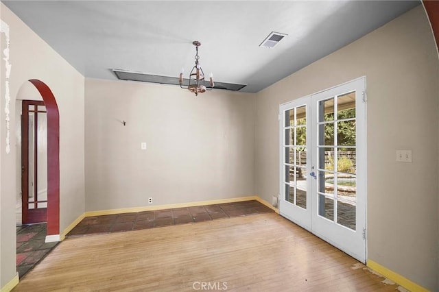 unfurnished dining area with hardwood / wood-style floors, french doors, and a chandelier