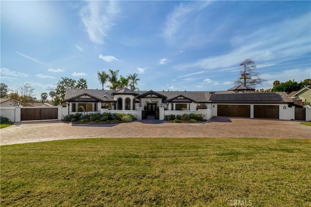 view of front of home with a garage, a front lawn, and solar panels