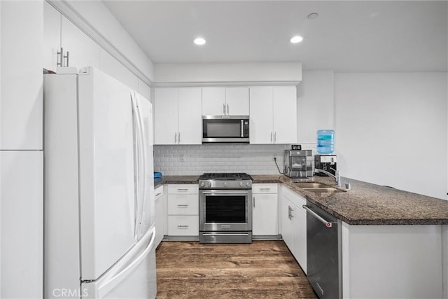 kitchen featuring sink, white cabinetry, appliances with stainless steel finishes, dark hardwood / wood-style flooring, and kitchen peninsula